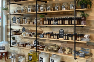 Juniper Seed Mercantile's shelves with various jars and bottles, soaps, plants.