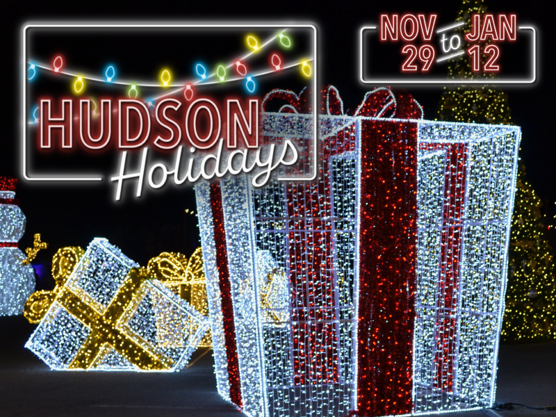 Image of a neon 'Hudson Holidays' logo overlayed on top of large-scale light structures shaped like presents and ornaments