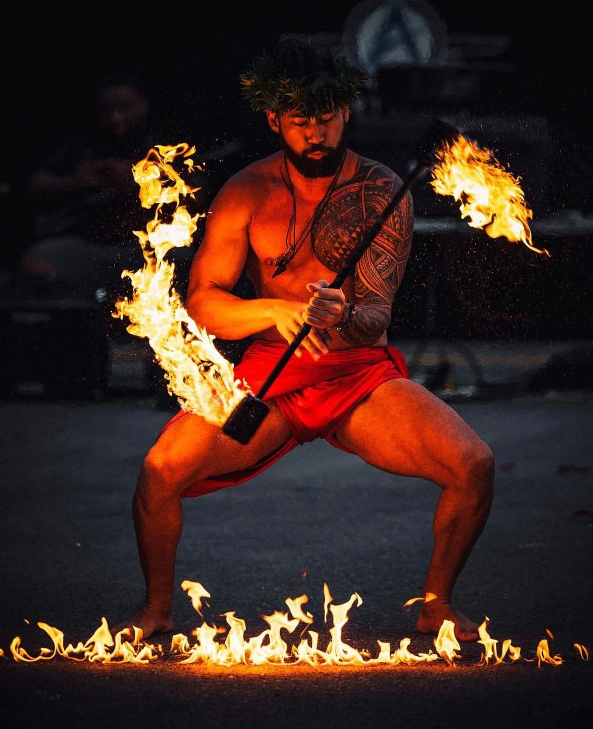 Man holding up flaming torch in front of a sunset
