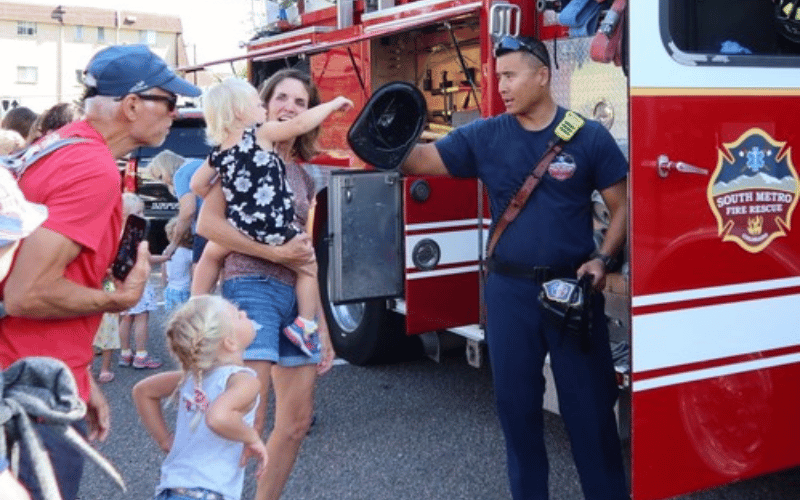 South Suburban firefighter giving a hat to a family in front of a fire truck