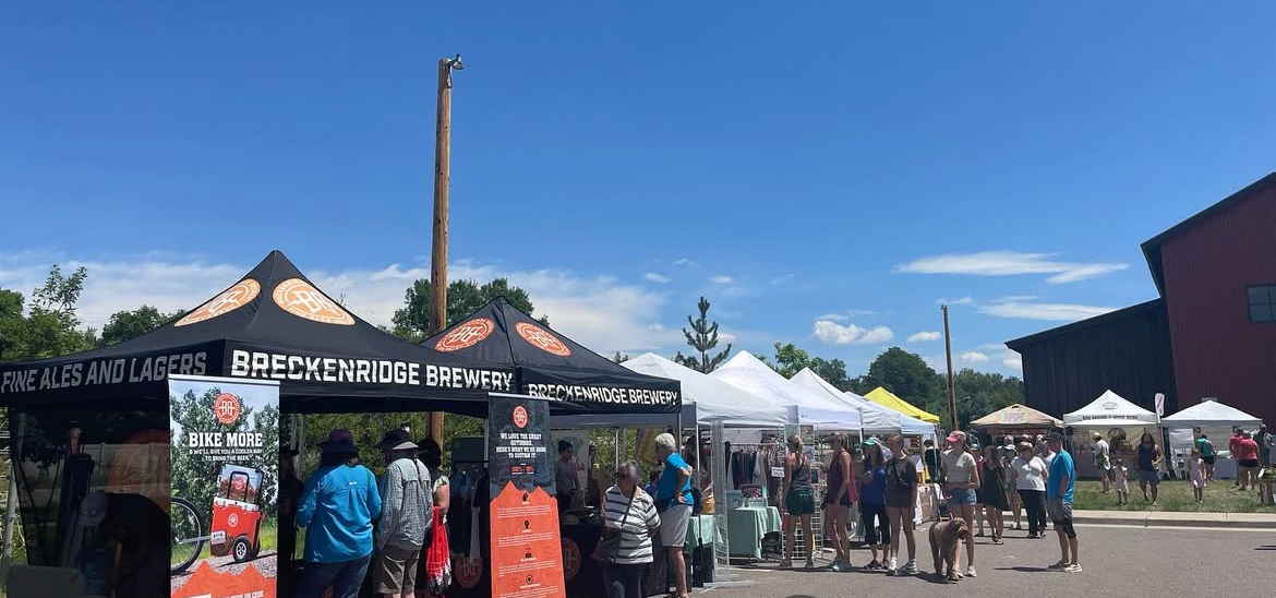 Artisan market tents, shoppers browsing and bright blue sky