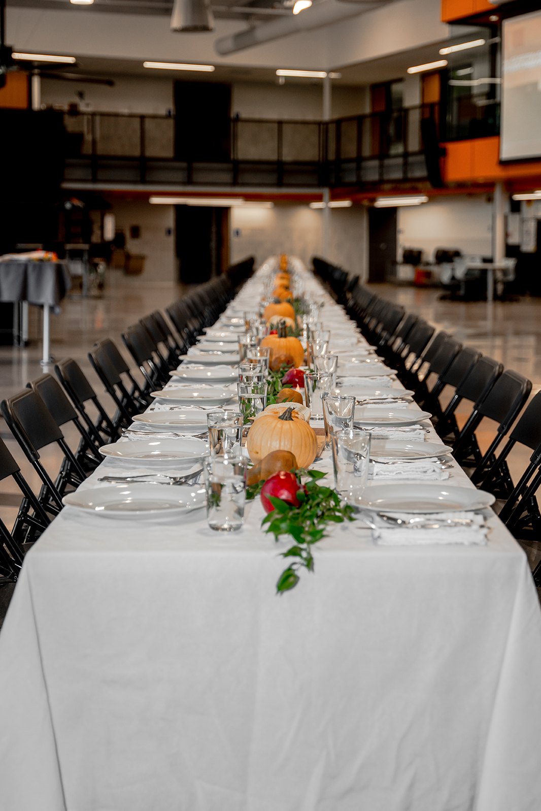 A large, long table with place settings for dozens of seats inside a large room.