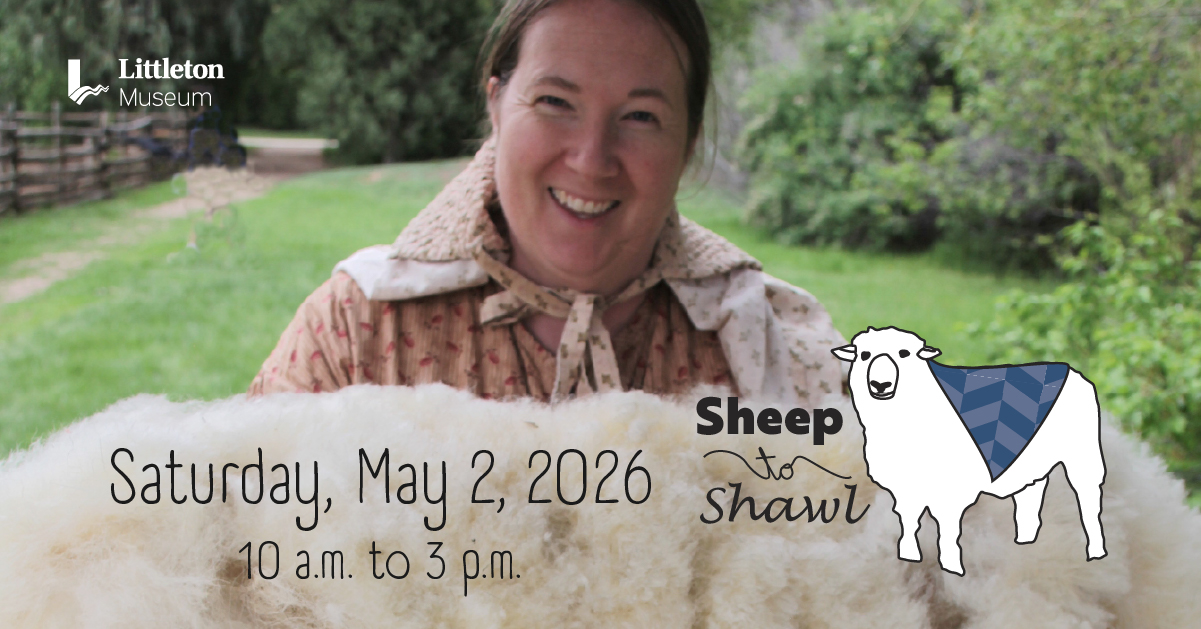 Smiling woman in a prairie dress holding up a white fleece just shorn off of a sheep
