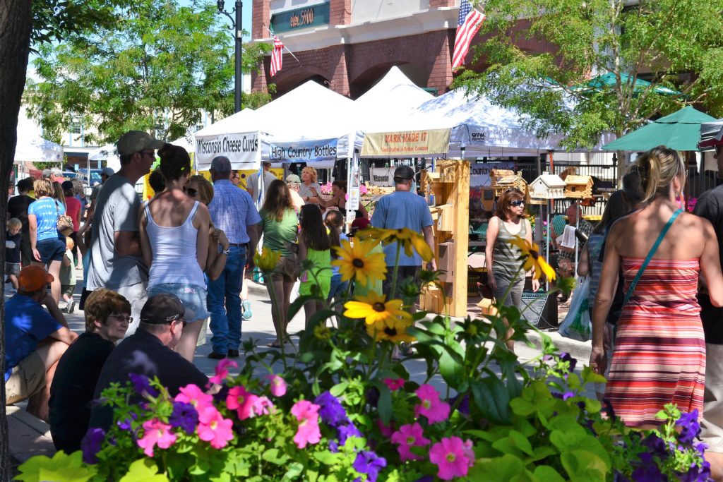 people shopping at outdoor market with vendor tents in summer time